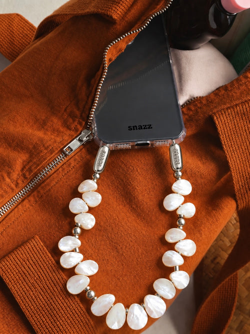 Petal Pearl phone chain on a clear Snazz iPhone case peeking out of a rust-coloured bag